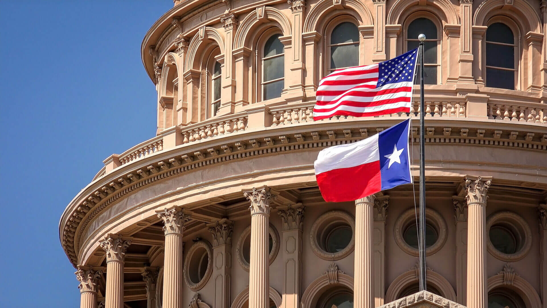 American and Texas Flags Flying at the Texas State Capitol Building in Austin